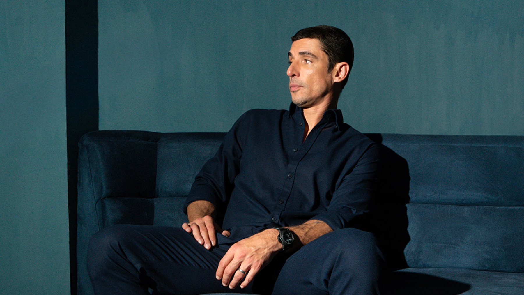 Alberto Guerra sitting on a dark blue sofa