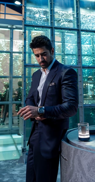 Jeremy Jauncey in a dark suit with Panerai watchbeside a glass wall