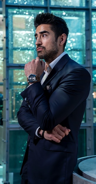 Jeremy Jauncey in a dark suit with Panerai watch beside a glass wall