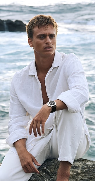Kauli Vaast in a white shirt with Panerai watch seated outdoors
